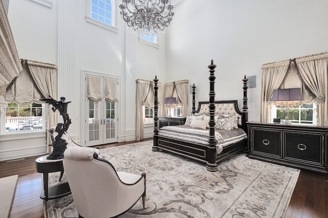 bedroom with a chandelier, dark hardwood / wood-style flooring, a high ceiling, and multiple windows