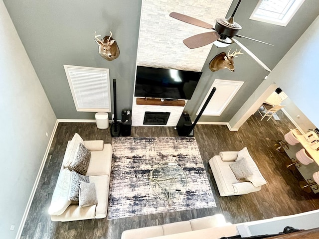 living room featuring a ceiling fan, wood finished floors, visible vents, baseboards, and a fireplace