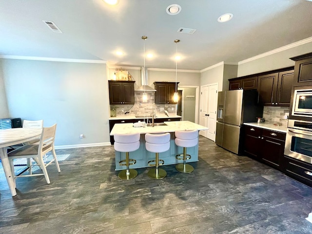 kitchen featuring visible vents, a sink, stainless steel appliances, light countertops, and a kitchen bar