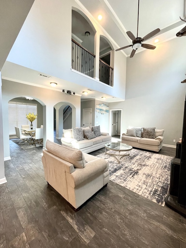 living room with wood finished floors, visible vents, baseboards, ceiling fan, and ornamental molding