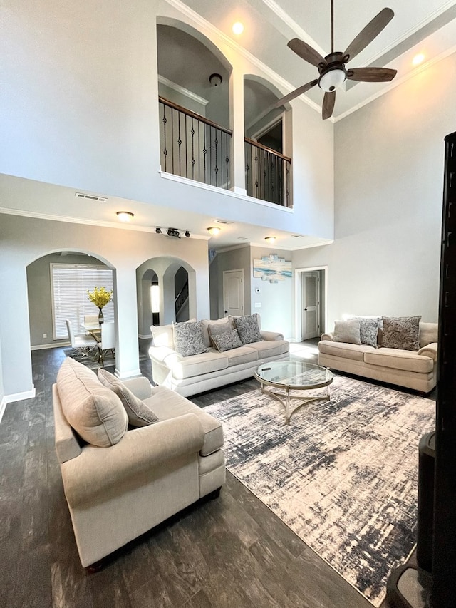 living room featuring visible vents, wood finished floors, arched walkways, and ornamental molding