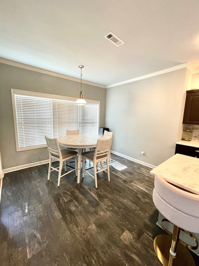 dining room featuring dark wood-style floors, visible vents, baseboards, and ornamental molding