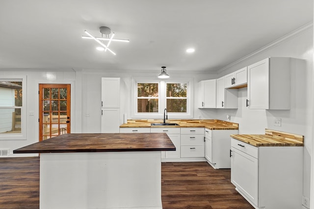 kitchen with wooden counters, dark hardwood / wood-style flooring, sink, a center island, and white cabinetry