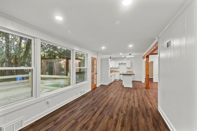 unfurnished living room featuring ornamental molding, dark hardwood / wood-style flooring, and a healthy amount of sunlight