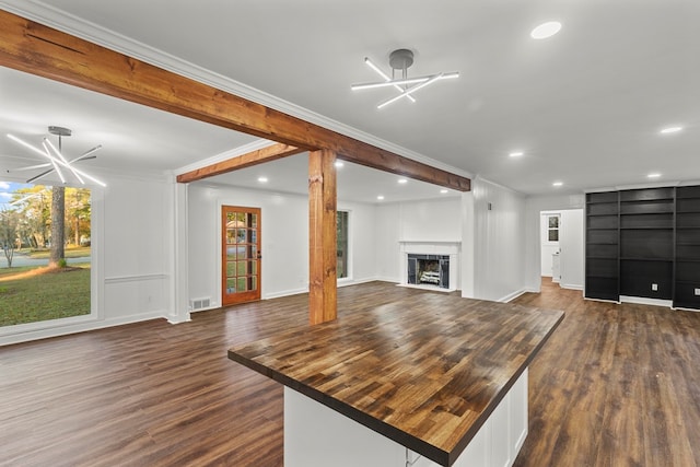 unfurnished living room with crown molding, dark hardwood / wood-style floors, and an inviting chandelier