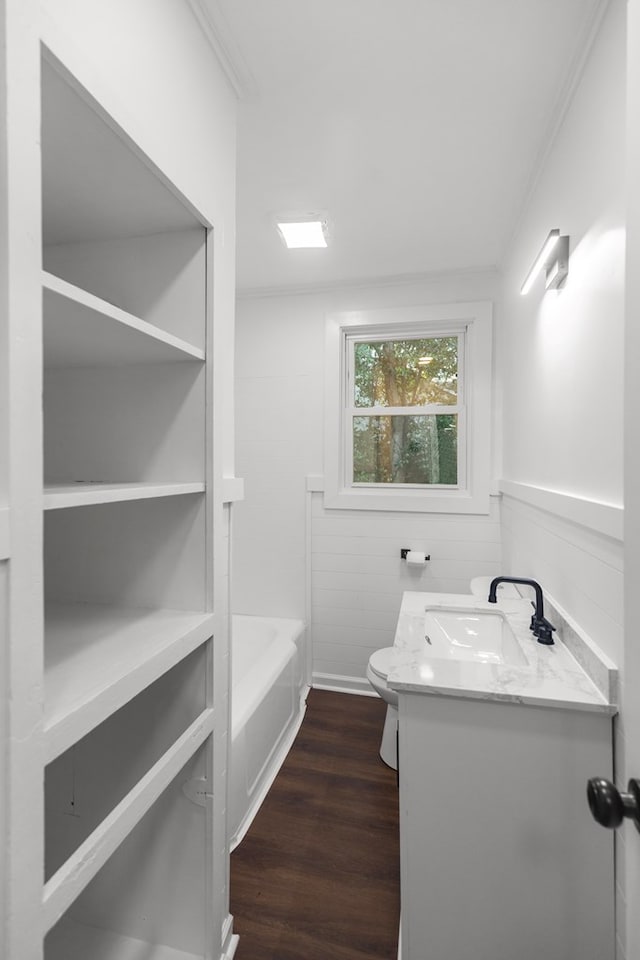 bathroom featuring a tub to relax in, vanity, hardwood / wood-style floors, toilet, and wood walls