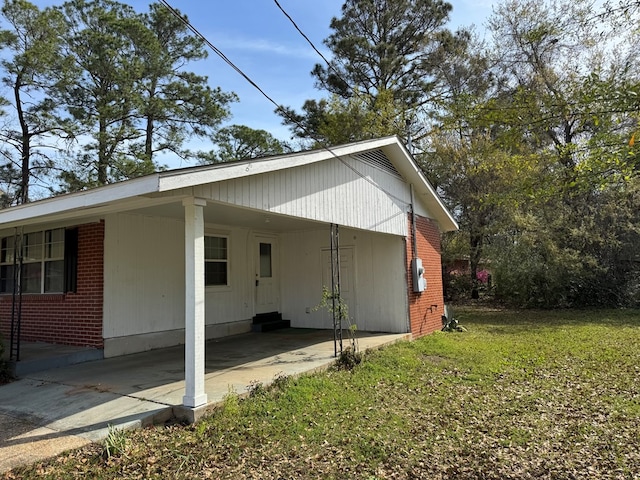 view of side of property with brick siding, a carport, and a lawn