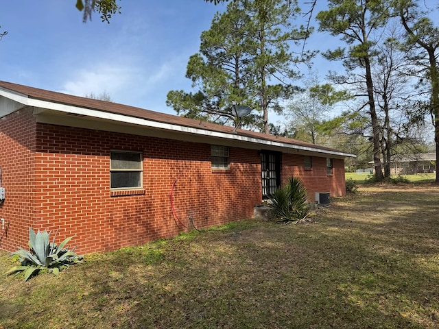 view of home's exterior featuring brick siding and a lawn