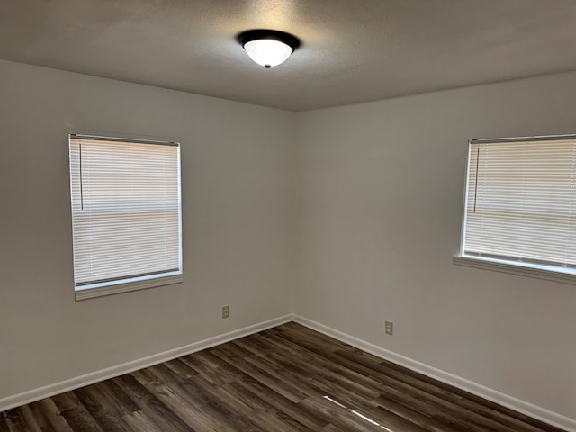 empty room featuring dark wood-style flooring, baseboards, and a textured ceiling