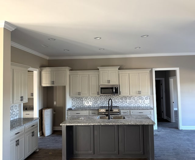 kitchen featuring white cabinets, light stone counters, a kitchen island with sink, and sink