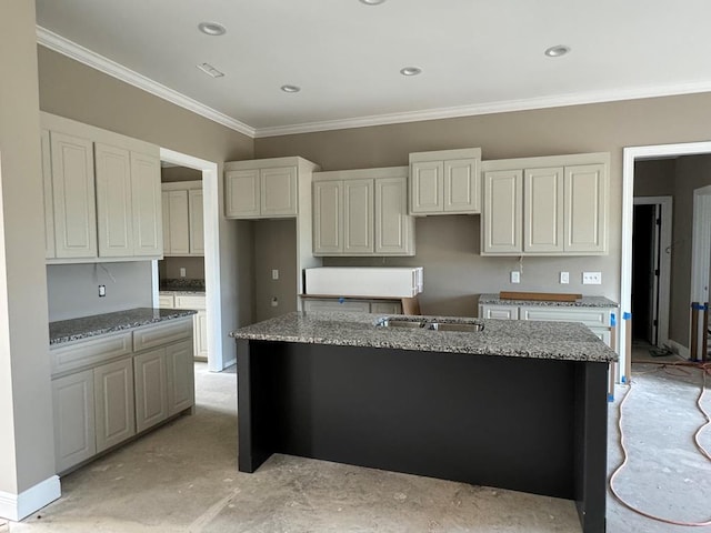 kitchen featuring light stone counters, a kitchen island with sink, and ornamental molding