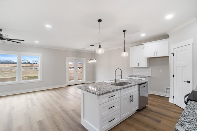 kitchen with sink, white cabinetry, light stone countertops, an island with sink, and stainless steel dishwasher