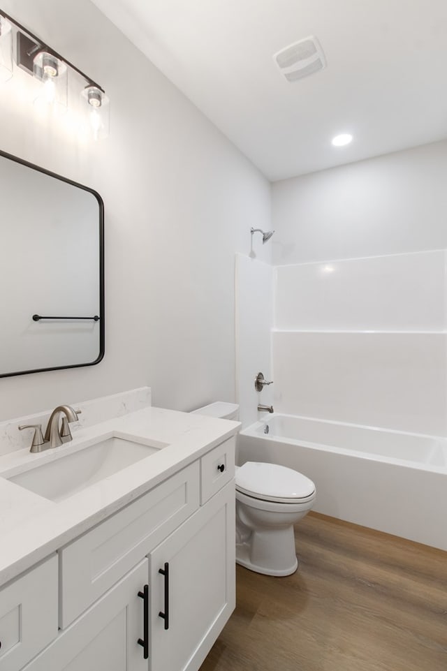 full bathroom with vanity, wood-type flooring, toilet, and washtub / shower combination