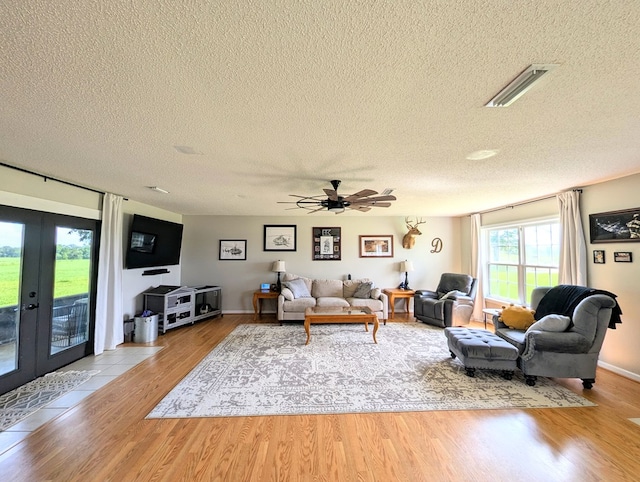 1370 Coach Rd, Slocomb, AL 36375 - living room featuring a textured ceiling, light wood-style flooring, ceiling fan, and french doors