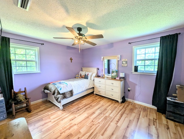 1370 Coach Rd, Slocomb, AL 36375 - bedroom featuring multiple windows, light wood-style flooring, a textured ceiling, and ceiling fan