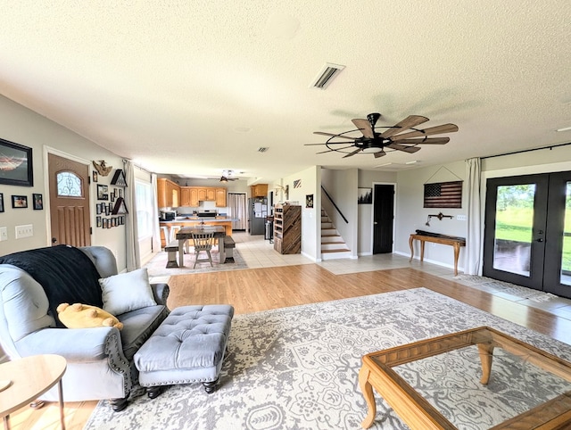 1370 Coach Rd, Slocomb, AL 36375 - living room with light wood-style flooring, plenty of natural light, stairway, a textured ceiling, and french doors