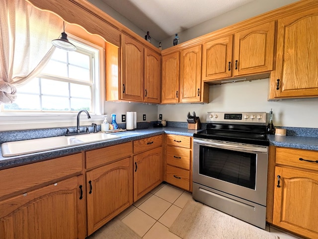 1370 Coach Rd, Slocomb, AL 36375 - kitchen with stainless steel range with electric cooktop, dark countertops, brown cabinets, and light tile patterned flooring