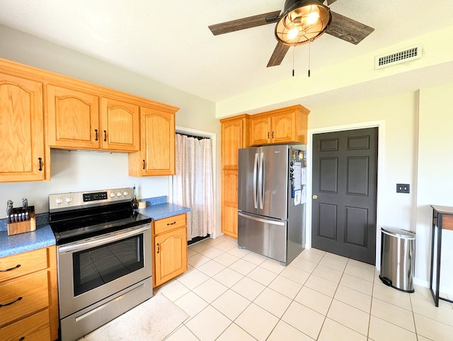 1370 Coach Rd, Slocomb, AL 36375 - kitchen with appliances with stainless steel finishes, ceiling fan, dark countertops, light tile patterned flooring, and light brown cabinetry