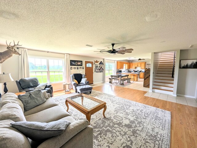 1370 Coach Rd, Slocomb, AL 36375 - living area featuring a textured ceiling, stairs, light wood-style floors, and a ceiling fan