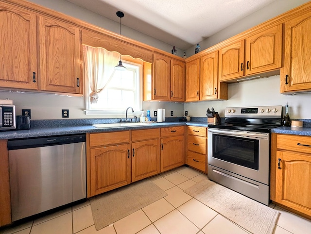 1370 Coach Rd, Slocomb, AL 36375 - kitchen with stainless steel appliances, dark countertops, brown cabinets, and pendant lighting