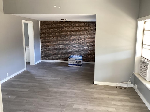 spare room featuring hardwood / wood-style flooring and brick wall