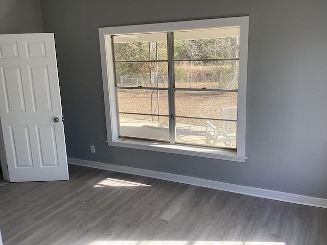 unfurnished room featuring baseboards and dark wood-style floors