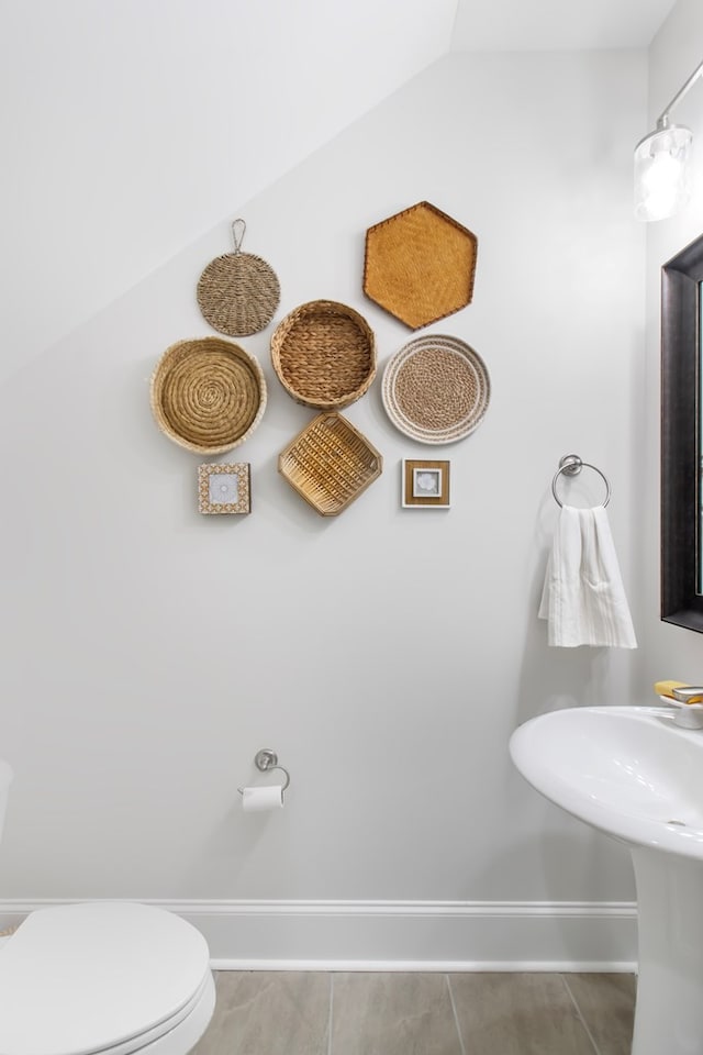 bathroom with tile patterned flooring, toilet, and lofted ceiling