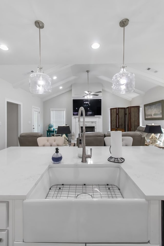 kitchen featuring ceiling fan, hanging light fixtures, lofted ceiling, and sink