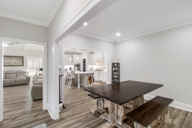 dining area with ceiling fan, crown molding, and light hardwood / wood-style flooring