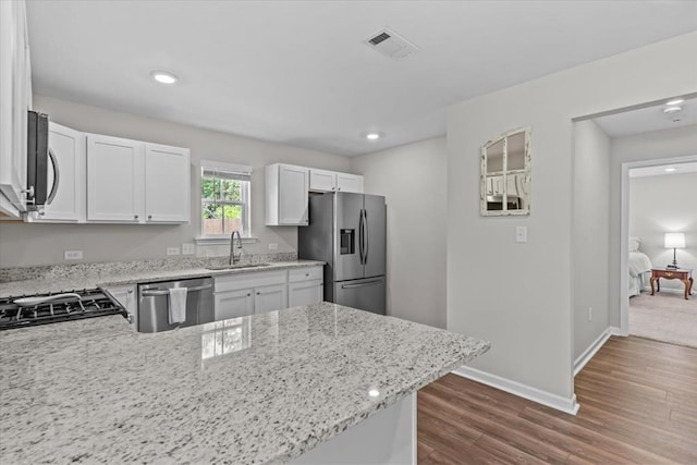 630 Ridgeland Rd, Dothan, AL 36301 - kitchen with stainless steel appliances, light stone counters, white cabinetry, a peninsula, and dark wood-type flooring