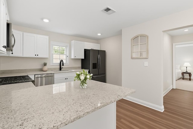 630 Ridgeland Rd, Dothan, AL 36301 - kitchen featuring appliances with stainless steel finishes, dark wood-style flooring, a peninsula, light stone countertops, and recessed lighting