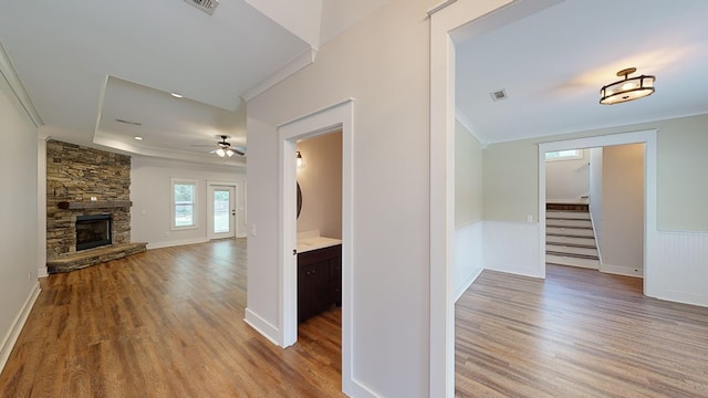 corridor with light hardwood / wood-style floors and ornamental molding