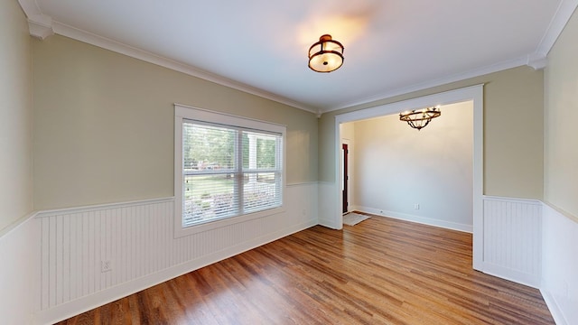 unfurnished room featuring an inviting chandelier, crown molding, and light hardwood / wood-style flooring