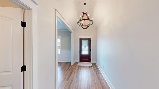 entryway featuring wood-type flooring, an inviting chandelier, and crown molding