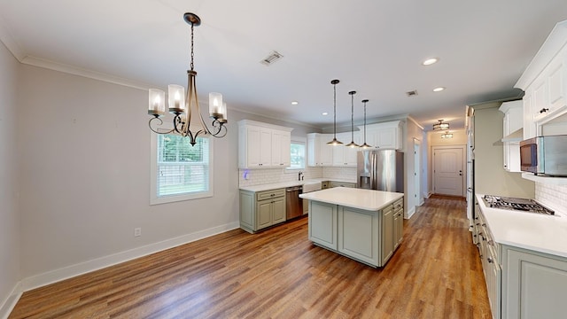 kitchen featuring appliances with stainless steel finishes, light wood-type flooring, a center island, white cabinetry, and hanging light fixtures