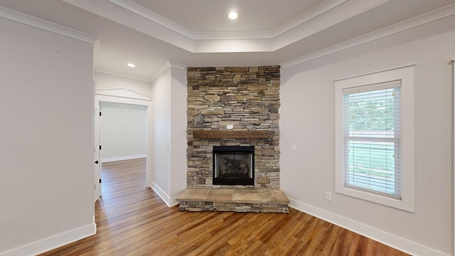 unfurnished living room featuring a stone fireplace, crown molding, and hardwood / wood-style flooring