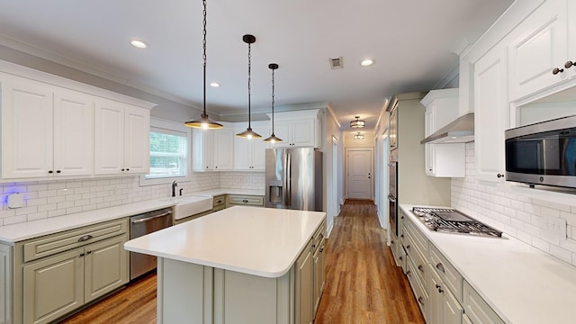 kitchen featuring a center island, white cabinets, crown molding, appliances with stainless steel finishes, and tasteful backsplash