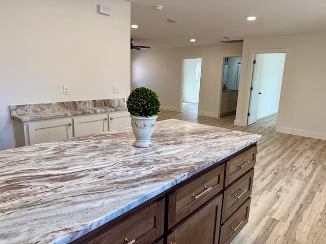 kitchen with dark brown cabinetry, ceiling fan, light stone counters, light hardwood / wood-style floors, and white cabinets