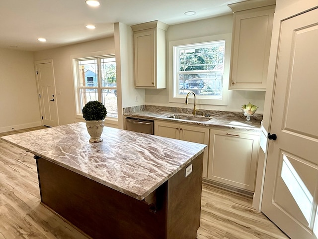 kitchen featuring light stone countertops, sink, light hardwood / wood-style flooring, dishwasher, and a kitchen island