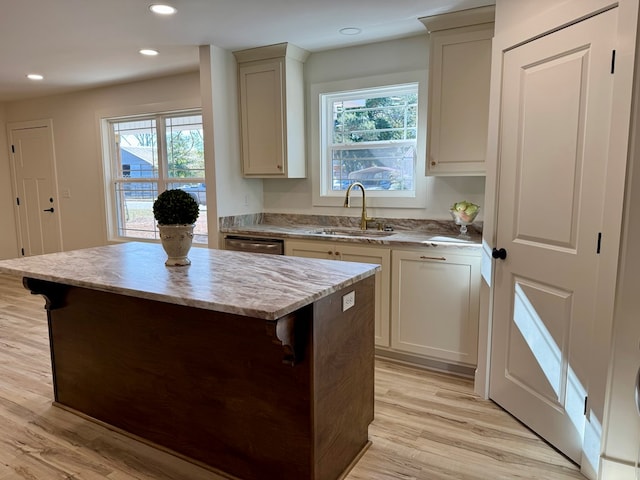 kitchen featuring light wood-type flooring, a breakfast bar, sink, dishwasher, and a center island