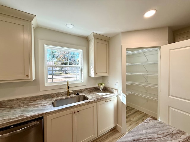 interior space featuring light stone countertops, dishwasher, light hardwood / wood-style floors, and sink