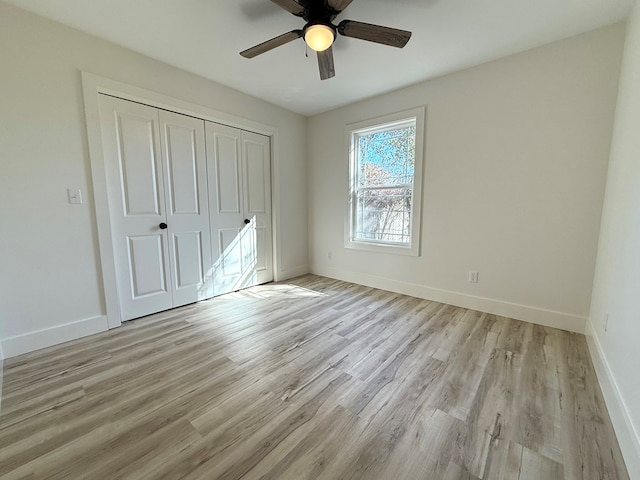 unfurnished bedroom featuring ceiling fan, light hardwood / wood-style floors, and a closet