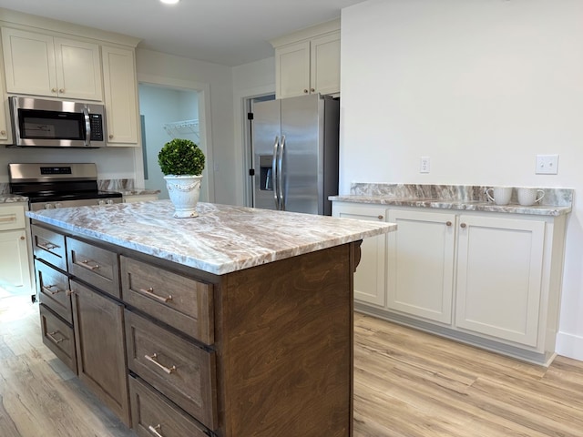 kitchen featuring dark brown cabinets, stainless steel appliances, a kitchen island, and light hardwood / wood-style flooring