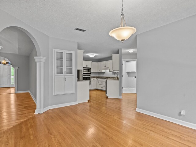 3602 Lake Oak Ridge Dr, Enterprise, AL 36330 - unfurnished living room with light wood finished floors, arched walkways, a textured ceiling, baseboards, and a sink