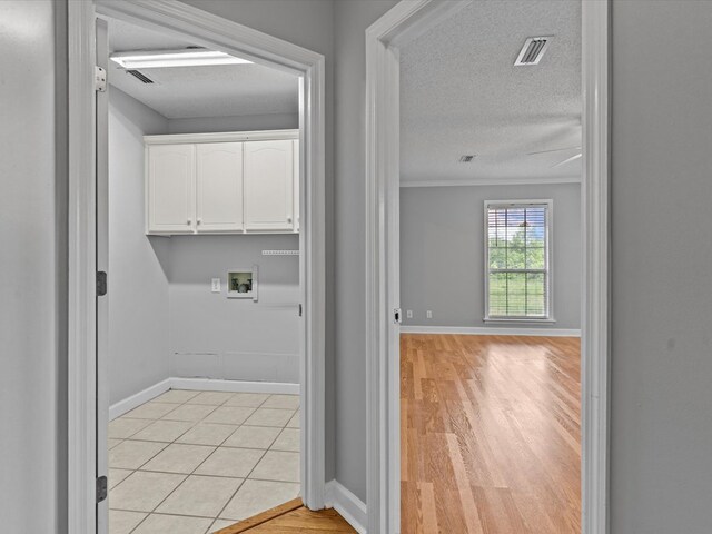 3602 Lake Oak Ridge Dr, Enterprise, AL 36330 - laundry area with cabinet space, washer hookup, a textured ceiling, baseboards, and light wood finished floors