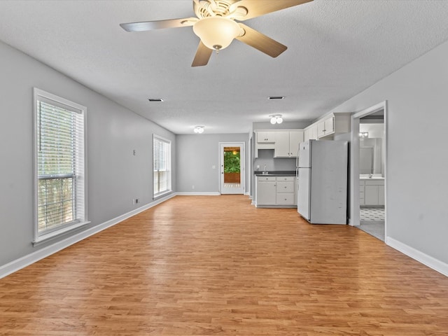 3602 Lake Oak Ridge Dr, Enterprise, AL 36330 - unfurnished living room featuring light wood-style floors, baseboards, a textured ceiling, a ceiling fan, and a sink