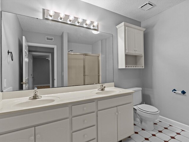 3602 Lake Oak Ridge Dr, Enterprise, AL 36330 - bathroom with a textured ceiling, a shower stall, double vanity, toilet, and tile patterned floors