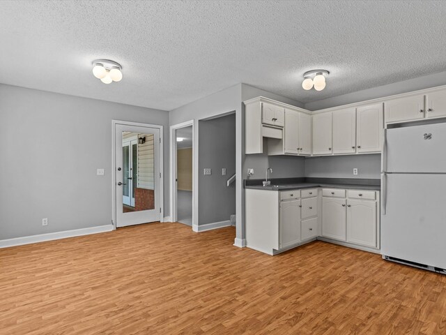 3602 Lake Oak Ridge Dr, Enterprise, AL 36330 - kitchen featuring freestanding refrigerator, dark countertops, light wood finished floors, white cabinetry, and a textured ceiling