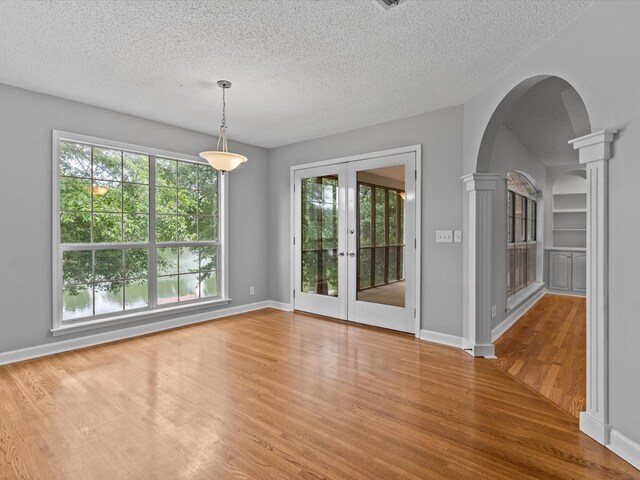 3602 Lake Oak Ridge Dr, Enterprise, AL 36330 - unfurnished room featuring arched walkways, wood finished floors, healthy amount of natural light, decorative columns, and a textured ceiling