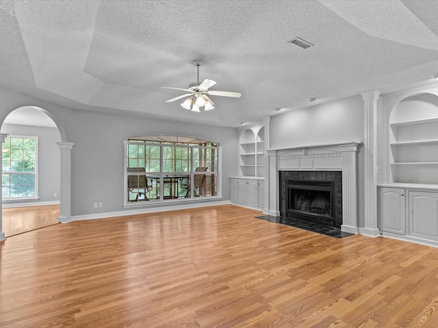 3602 Lake Oak Ridge Dr, Enterprise, AL 36330 - unfurnished living room featuring light wood finished floors, ceiling fan, a textured ceiling, a tile fireplace, and built in shelves